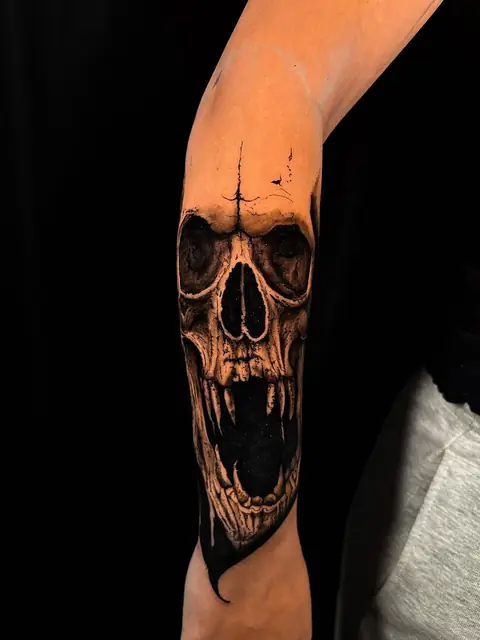 Fauchender Totenkopf mit Reißzähnen in Black & Grey auf dem Unterarm