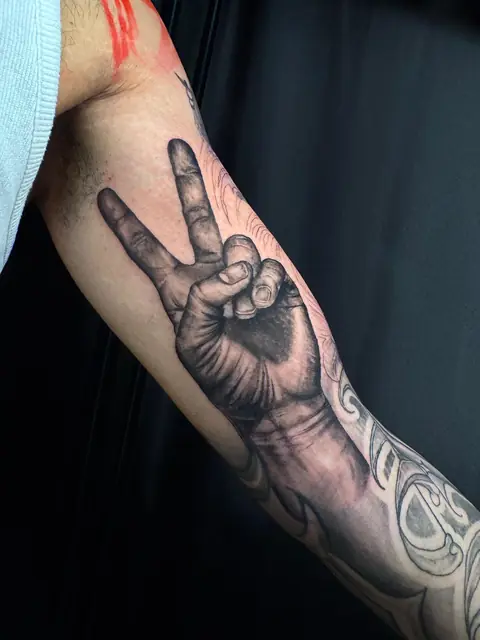 Realistische Hand mit Peace-Zeichen, übergehend in Lettering-Sleeve auf dem Unterarm